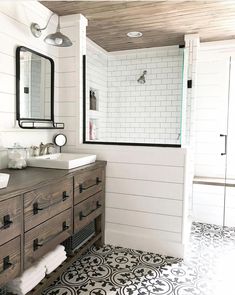 a bathroom with white walls and black and white flooring, two sinks on the vanity