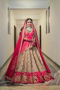 a woman in a red and gold bridal gown poses for the camera on her wedding day