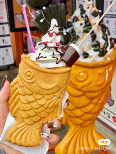 a person holding an ice cream sundae in front of two large yellow vases