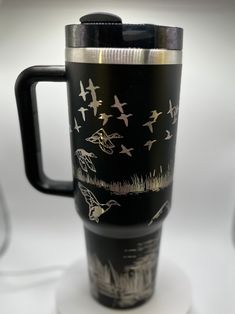 there is a black coffee cup with birds on it