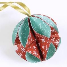 an origami ball with gold ribbon hanging from it's side on a white background