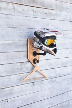 a pair of ski goggles hanging on a wooden hanger next to a wall