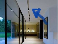 an empty hallway with glass walls and blue arrows on the wall in front of it