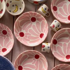 pink and white bowls with designs on them are sitting on a wooden surface next to other dishes