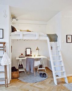 there is a loft bed with a desk and ladder in the room that has pictures on the wall