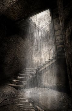 an open door leading into a dark room with stairs and light coming from the window