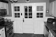 black and white photo of kitchen with stove, oven, microwave and cabinets in it