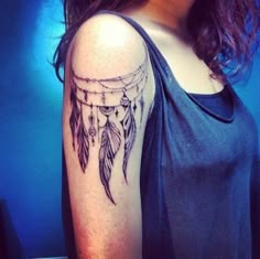 a woman's arm with a black and white dream catcher tattoo on her left shoulder