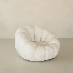 a white round chair sitting on top of a gray floor next to a beige wall