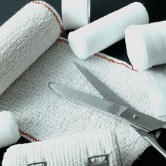 a pair of scissors sitting on top of white towels next to rolls of toilet paper