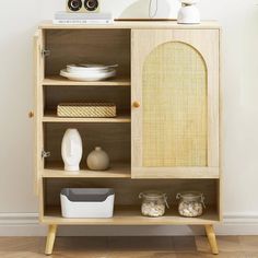 a wooden cabinet with baskets and bowls on it's shelves next to a white wall