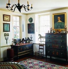 a living room filled with furniture and paintings on the wall next to a dresser covered in figurines