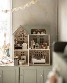 a doll house sitting on top of a dresser next to a window