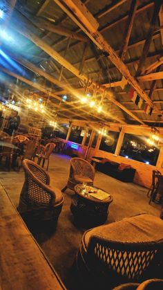 the inside of a restaurant with wicker chairs, tables and lights hanging from the ceiling