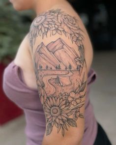 a woman with a mountain and flowers tattoo on her arm