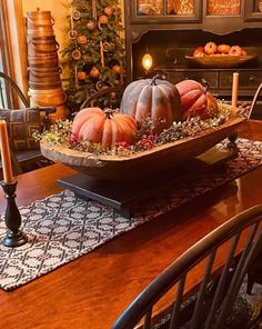 a wooden table topped with a bowl filled with pumpkins