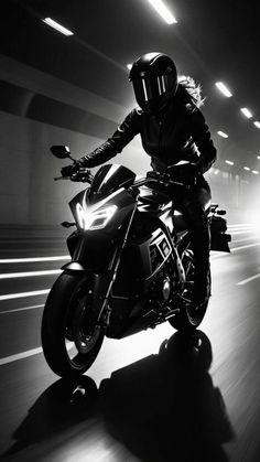 a person riding a motorcycle on a city street in the middle of an tunnel at night