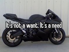 a black motorcycle parked in front of a white wall with the words it's not a want it's a need