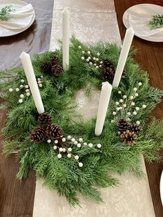 a christmas wreath with candles and pine cones