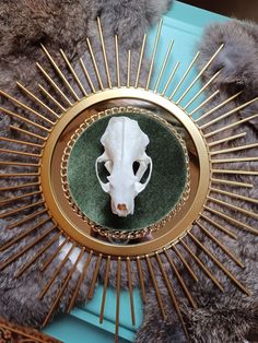 an animal skull is shown in the center of a gold and green decoration with spikes