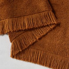 two pieces of brown fabric with fringes on top of each other in close up