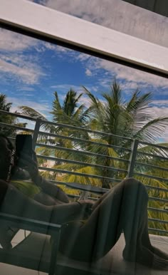 a man sitting in a chair looking at his cell phone while he is on the balcony