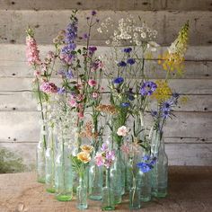 a group of vases filled with flowers on top of a wooden table