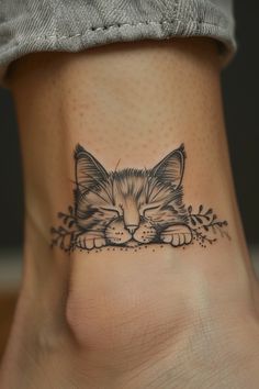 a small kitten tattoo on the side of a woman's foot, with leaves around it