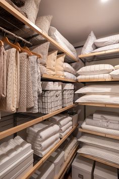 the shelves are filled with white linens and blankets