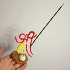 a hand holding an odd shaped object on a stick