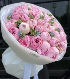 a bouquet of pink flowers sitting on top of a white ribbon