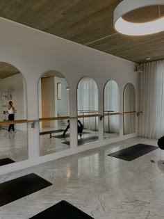 people doing yoga in a large room with mirrors on the wall and flooring around them