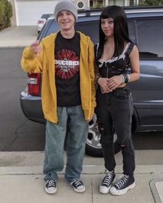 two people standing next to each other in front of a car