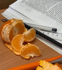 peeled oranges on a cutting board next to a pair of scissors and an open book