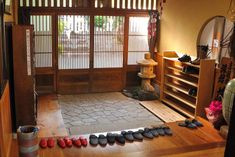 there are many pairs of shoes on the floor in front of an open door that leads to another room