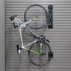 a bike hanging on the side of a garage door next to a wall mounted bicycle rack