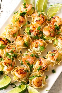 shrimp and tortilla shells with lime wedges on a white platter, ready to be served