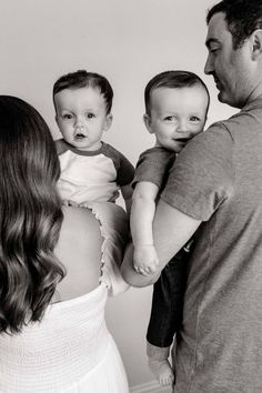 a black and white photo of a man holding two babies