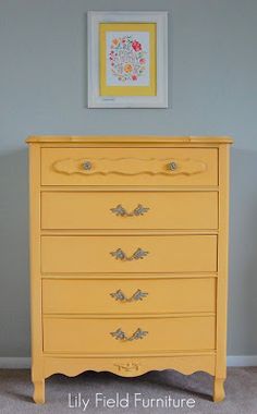 a yellow dresser in a room with a framed picture on the wall and carpeted floor