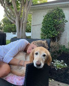 a woman laying on top of a chair next to a brown dog with her eyes closed