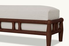 an upholstered footstool with white cushions and wood trim on the legs