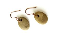 two brown stone earrings are hanging from copper hooks on a white surface with a black bead