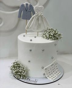 a white wedding cake with flowers and a dress on top is decorated with baby's breath