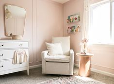 a white chair sitting next to a window in a room with pink walls and carpet