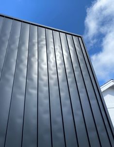 the side of a building with some clouds in the sky