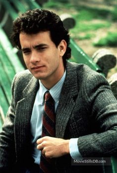 a man in a suit and tie sitting on a bench with his arms folded out