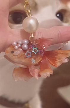 a close up of a person's hand holding a gold fish keychain