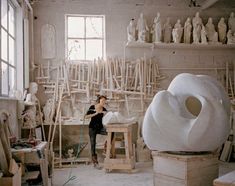 a woman is working in a studio with sculptures