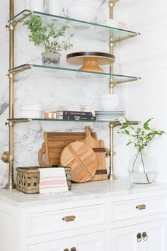 a kitchen with white cabinets and gold shelves