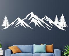 a living room with a blue couch and white mountain wall decal